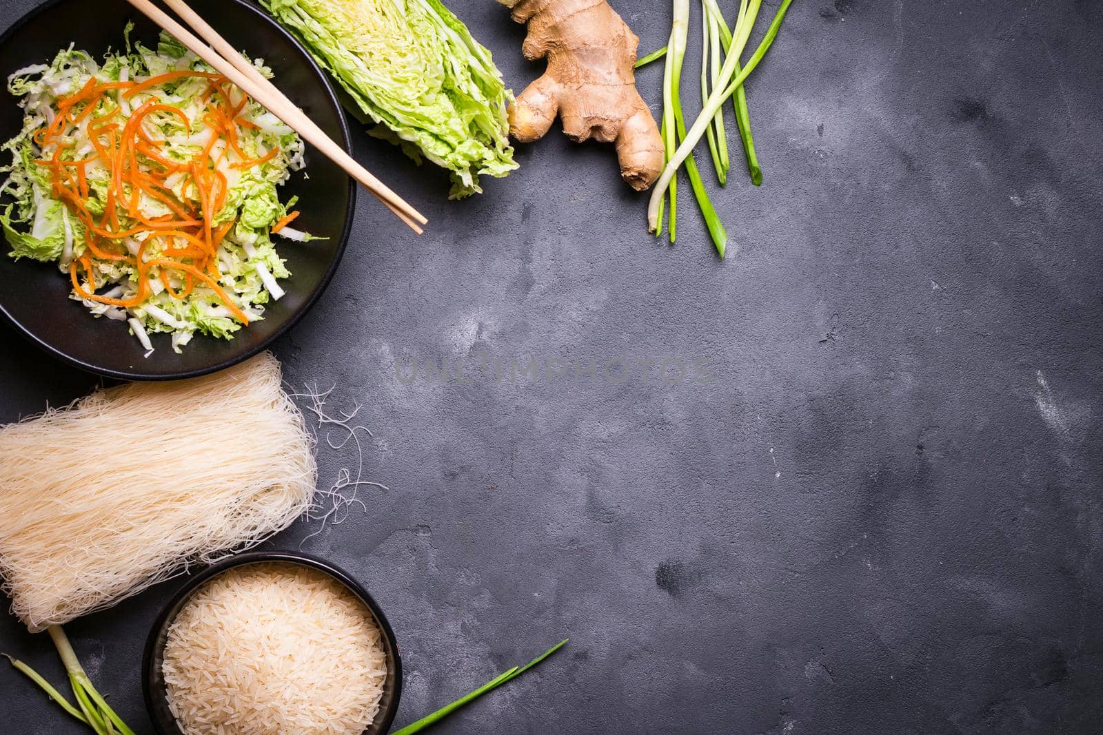 Ingredients for making chinese dinner: rice noodles, rice, napa cabbage, ginger, green onion. Asian cooking ingredients. Top view. Preparing healthy asian meal with vegetable salad. Space for text