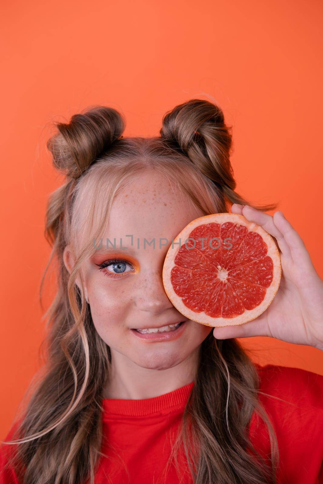 sweet joyful brunette girl female with cropped slice of grapefruit near skin face on orange background. tasty juicy fruit. Tropical citrus fruits, Healthy food. weight loss.