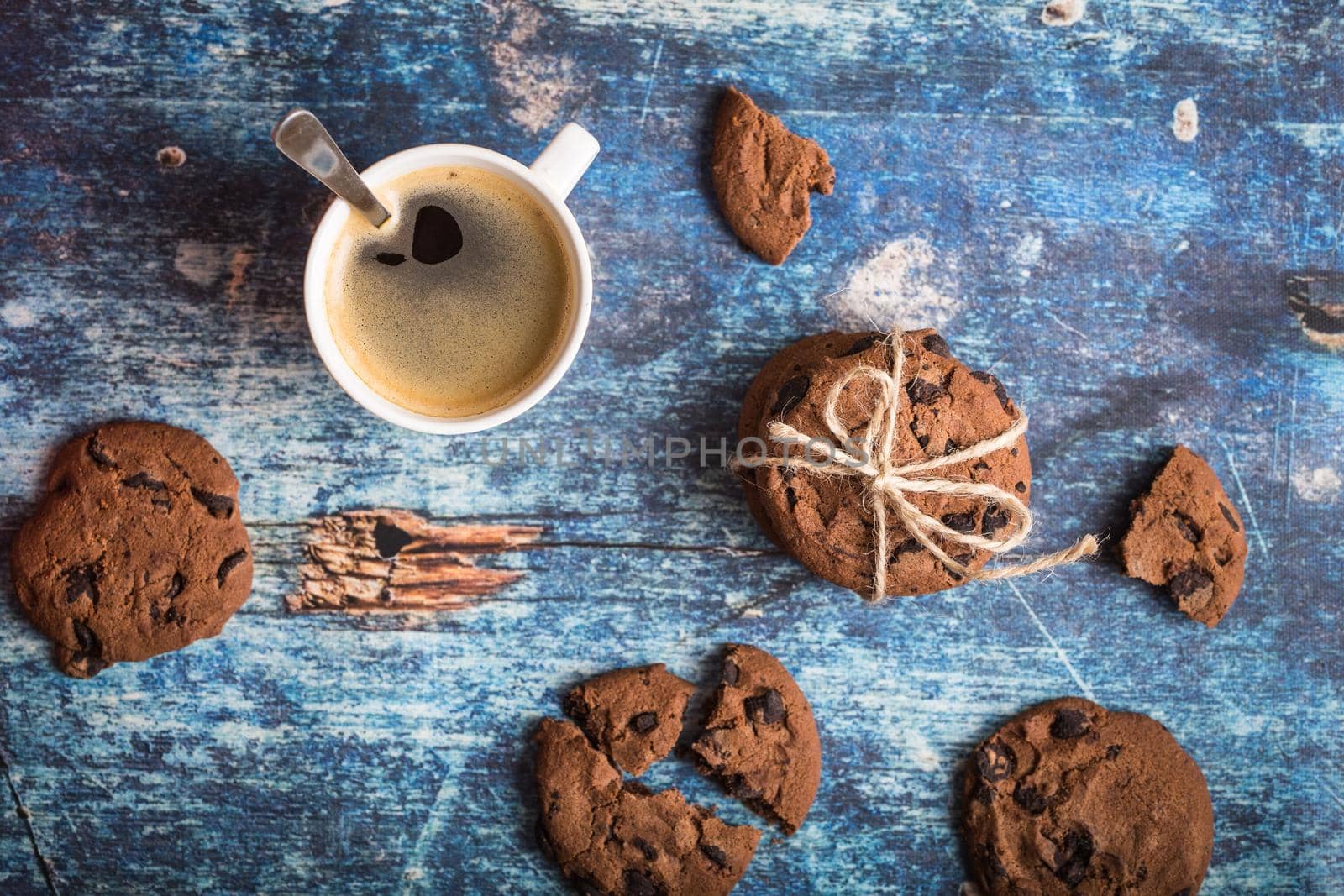 Cup of fresh hot coffee, chocolate cookies on old rustic blue wooden table. Vintage background. Morning coffee. Warm coffee, dessert for lunch. Espresso in white cup. Top view. Close up. From above