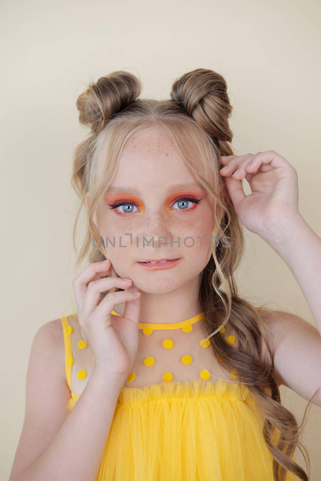 charming blonde tween girl with orange makeup on yellow background. teenager portrait by oliavesna