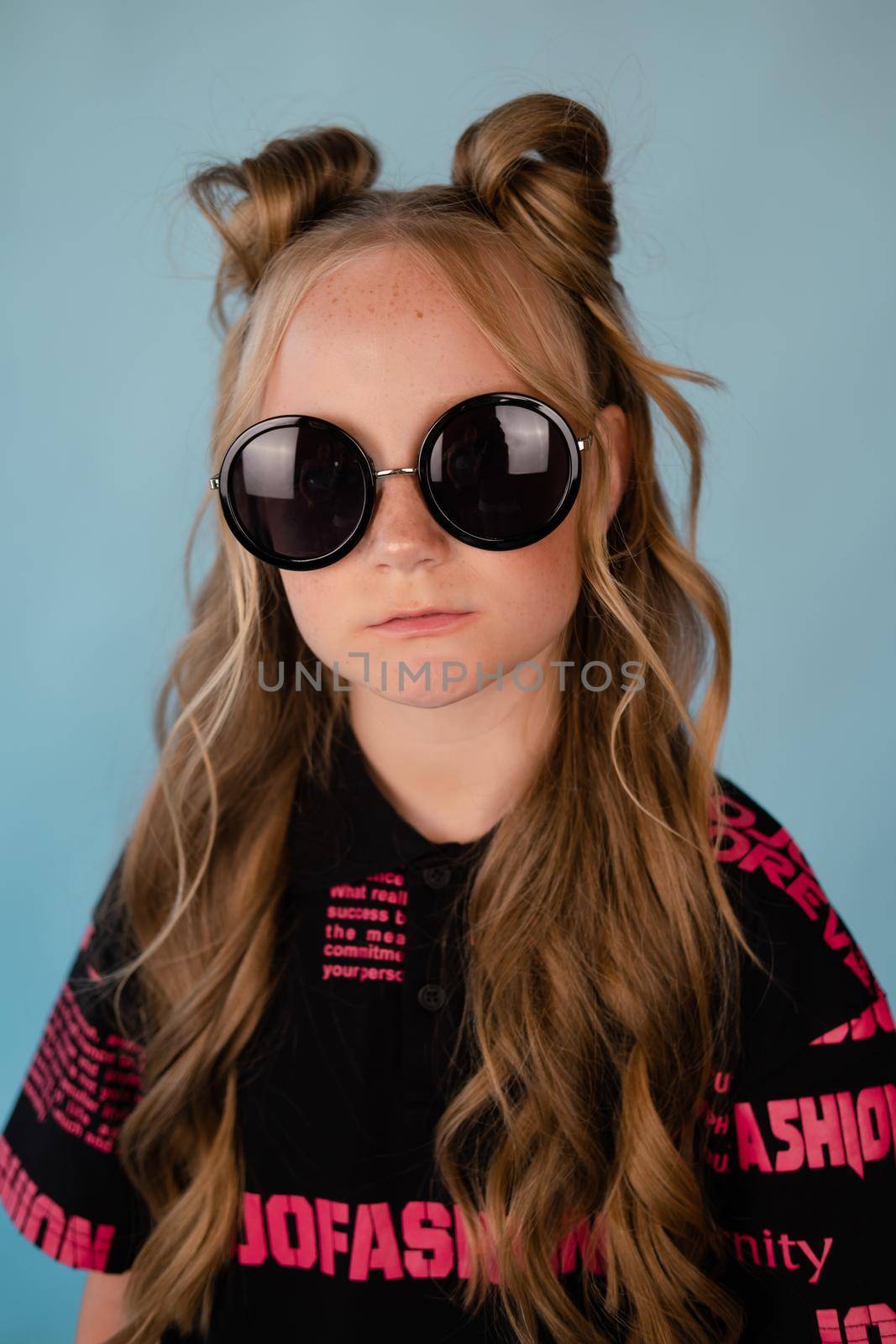 stylish teenage girl. tween school girl wearing pink fashion clothes on blue background. long hair and freckles.