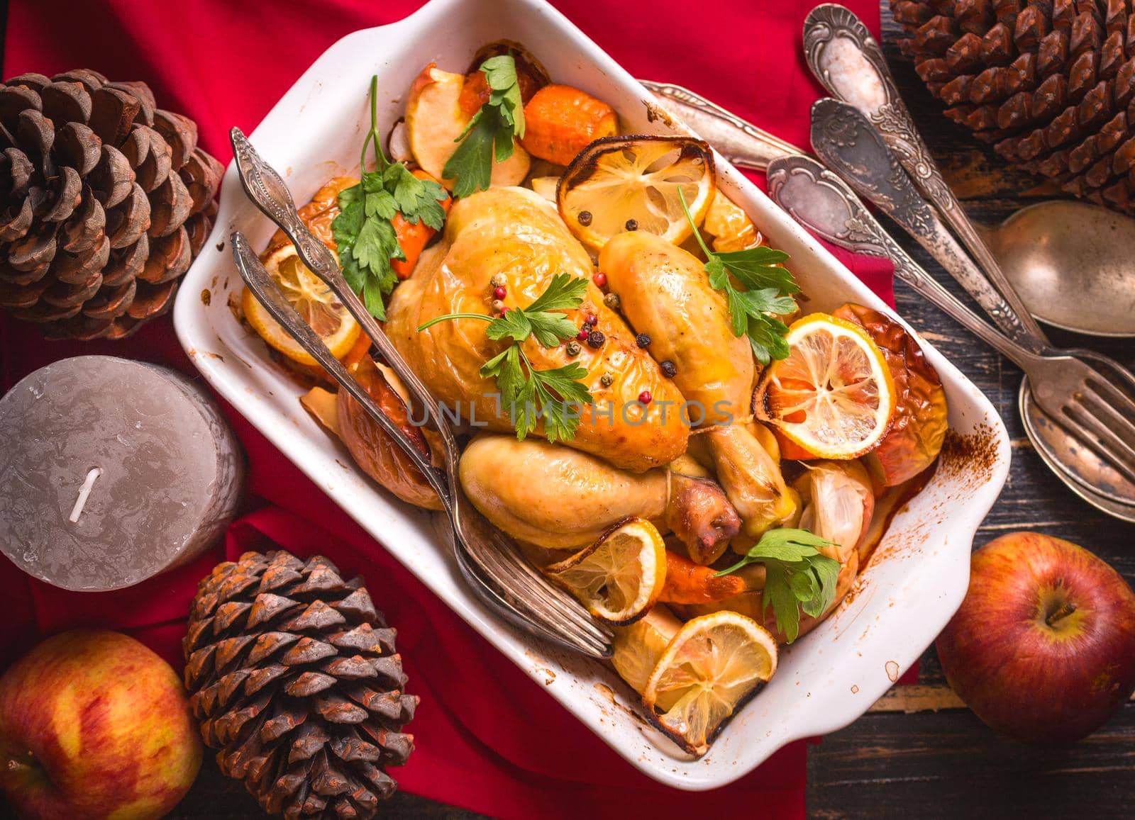 Roasted chicken. Christmas food. Rustic celebration table with roasted chicken, vegetables, apples, decorated with candles, vintage cutlery. Christmas/Thanksgiving dinner. Festive dinner. Top view