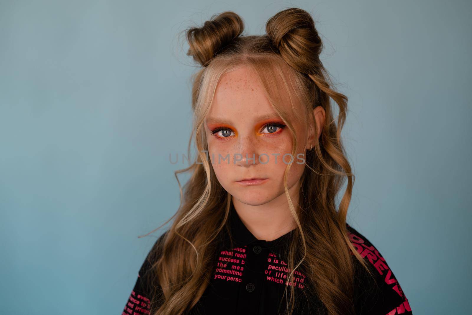 stylish teenage girl. tween school girl wearing pink fashion clothes on blue background. long hair and freckles.