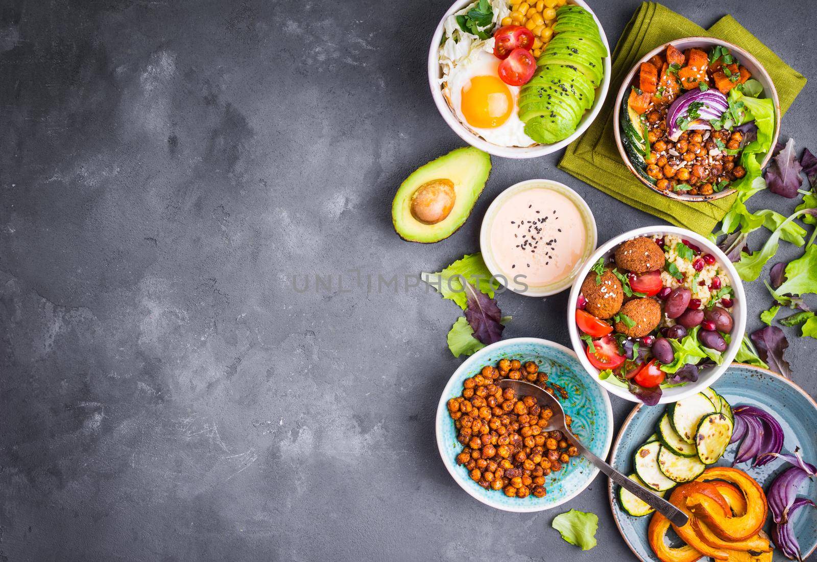 Mixed healthy vegetarian salads with vegetables, sweet potato, falafel, bulgur, avocado, eggs. Assorted buddha bowl salads background. Healthy dinner. Salad in bowl. Making ingredients. Space for text