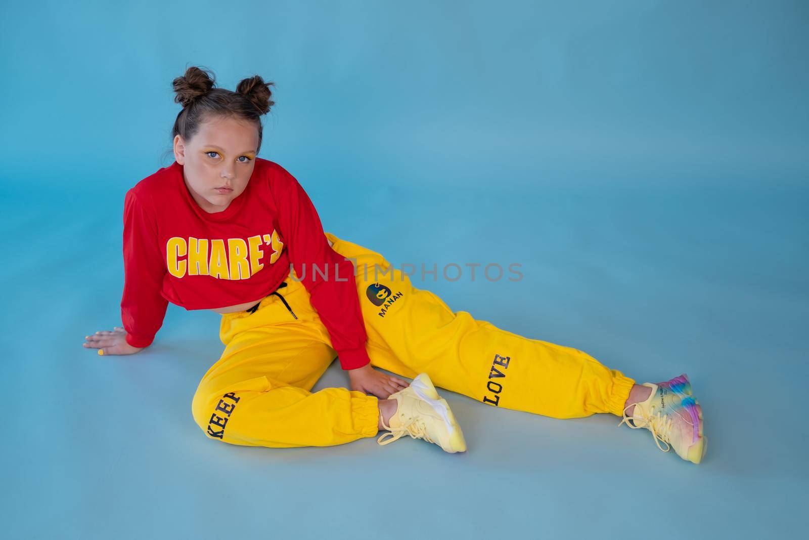 teenage girl in fashion stylish bright clothes. little lady in red and yellow on blue background. makeup and hairdo.