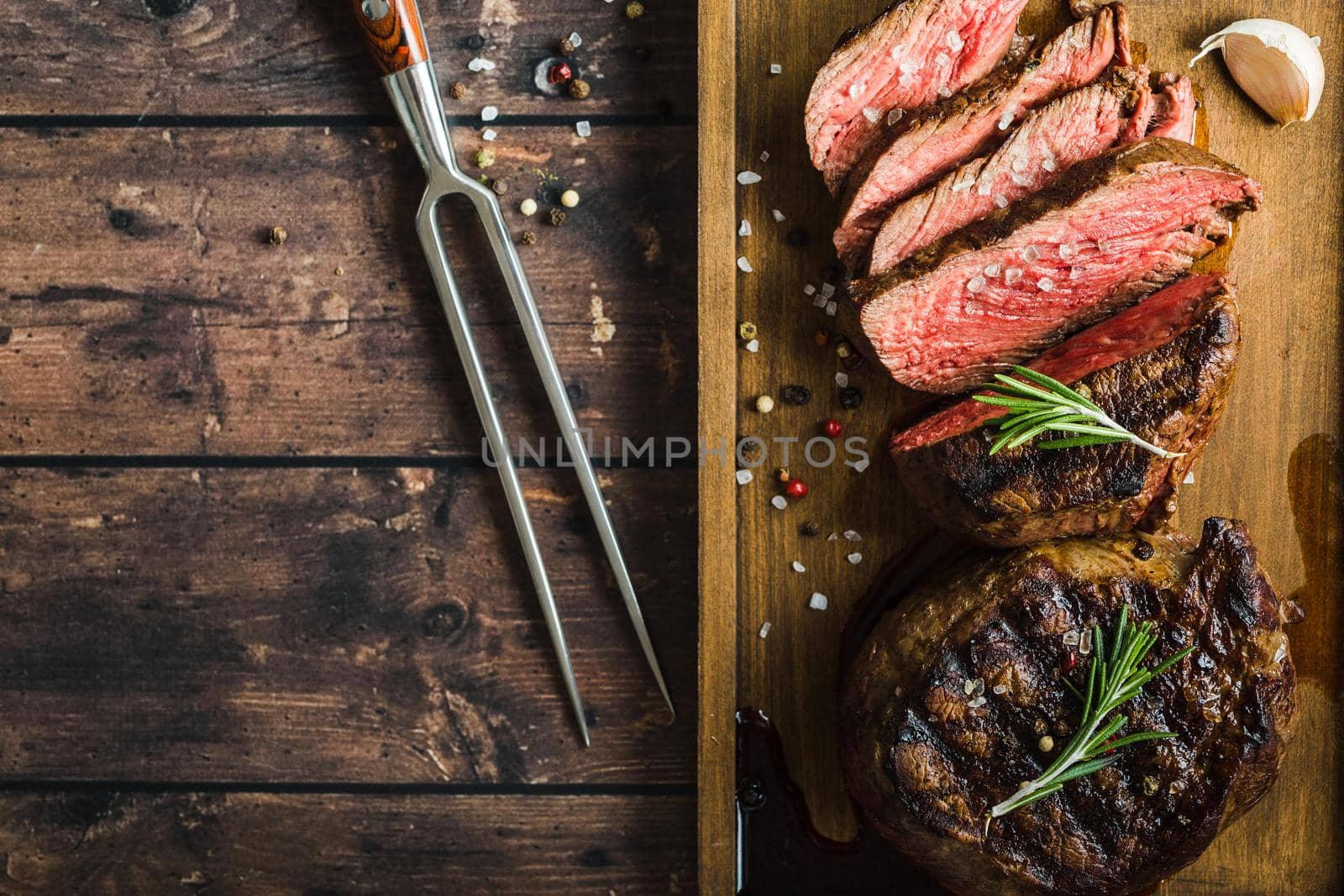 Sliced grilled marbled meat steak Filet Mignon, seasonings, fork, wooden cutting board. Space for text. Juicy meat steak. Beef steak grilled/fried. Top view. Roasted meat steak. Close-up. Rustic