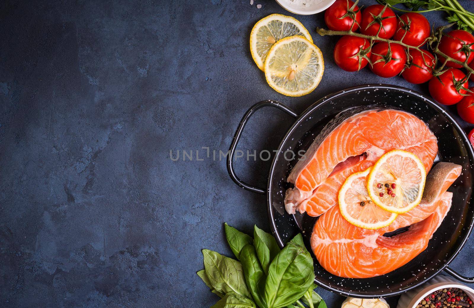 Raw fresh fish with vegetables ready to cook. Raw salmon steak with lemon and spices in a pan. Ingredients for cooking on a concrete background. Space for text. Diet and healthy food. Fish background