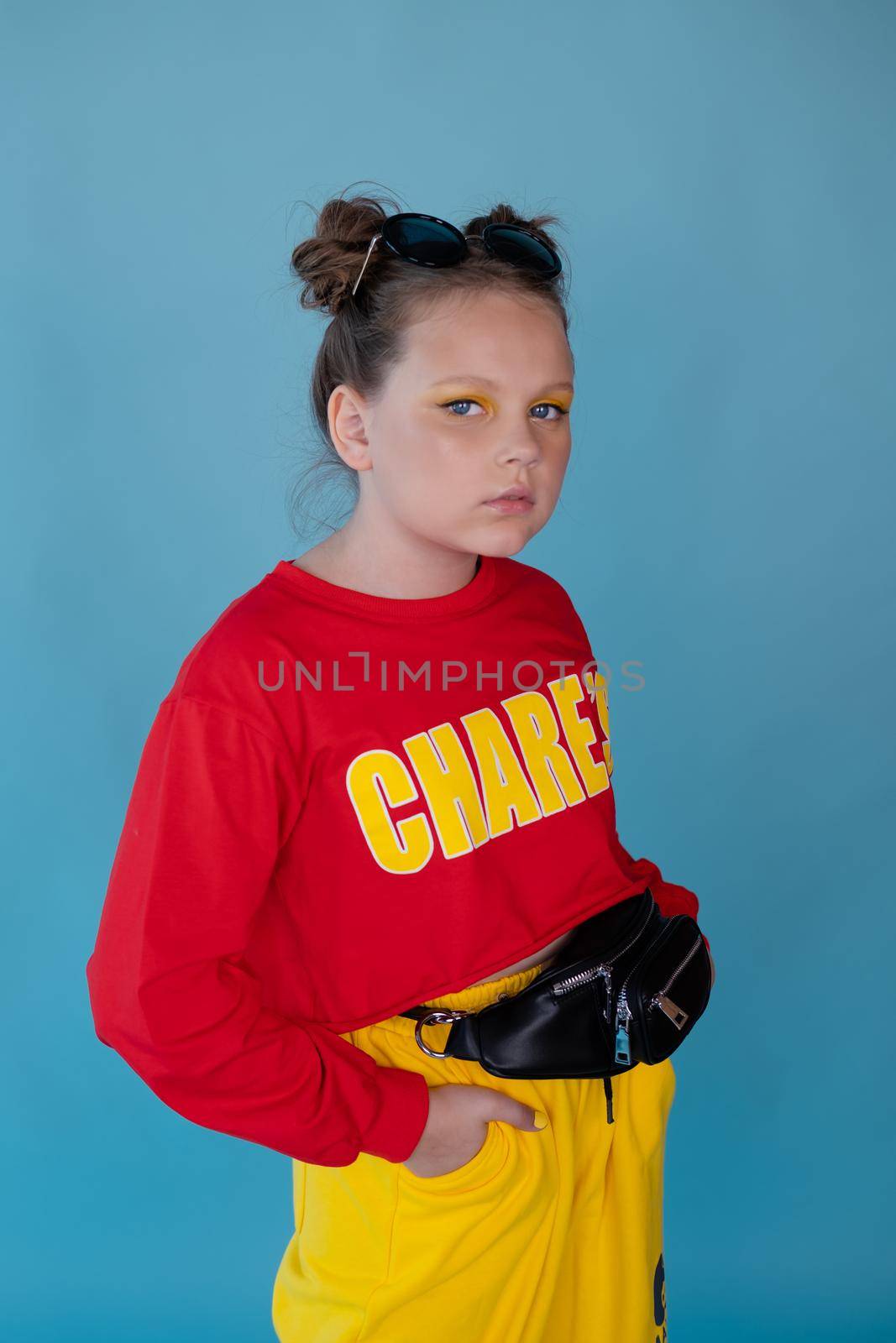 teenage girl in fashion stylish bright clothes. little lady in red and yellow on blue background. makeup and hairdo.