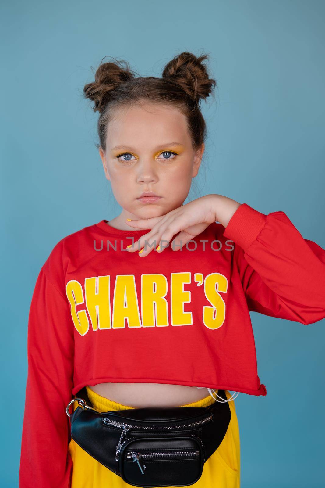 teenage girl in fashion stylish bright clothes. little lady in red and yellow on blue background. makeup and hairdo.