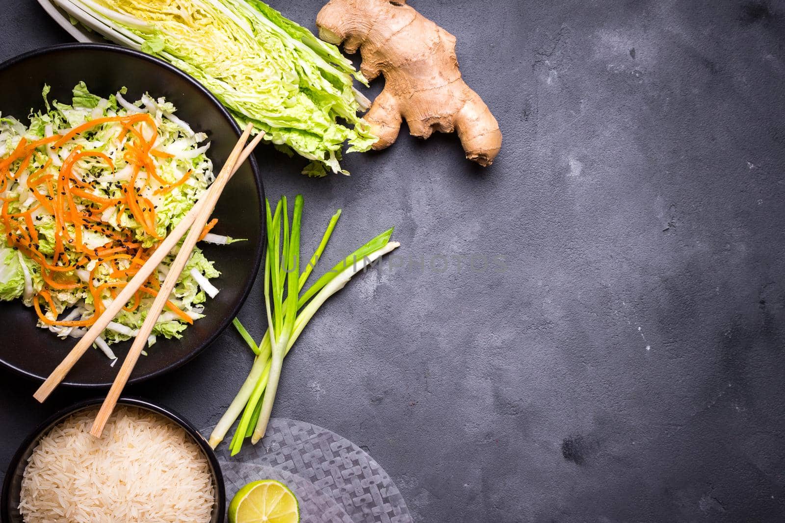 Ingredients for cooking vietnamese dinner: rice paper, rice, napa cabbage, ginger, green onion, salad. Asian cooking ingredients. Top view. Making vietnamese vegetable spring rolls. Space for text