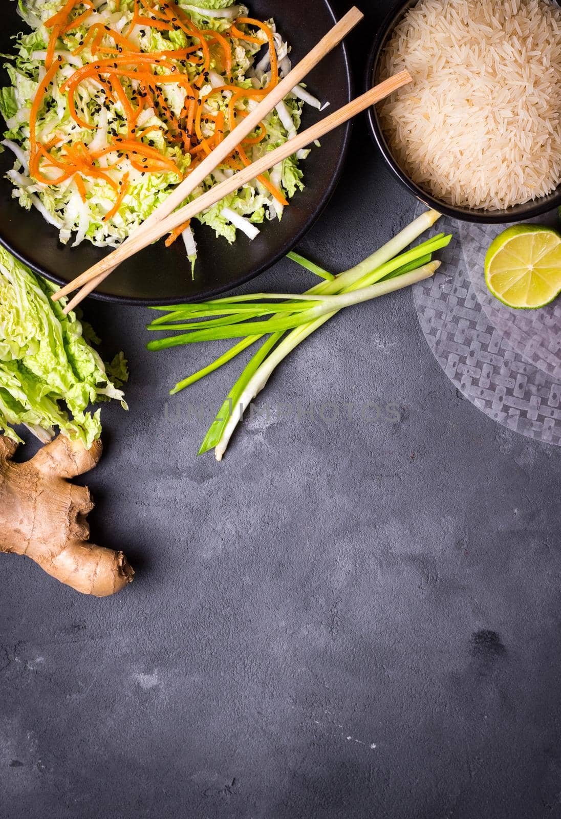 Ingredients for cooking vietnamese dinner: rice paper, rice, napa cabbage, ginger, green onion, salad. Asian cooking ingredients. Top view. Making vietnamese vegetable spring rolls. Space for text