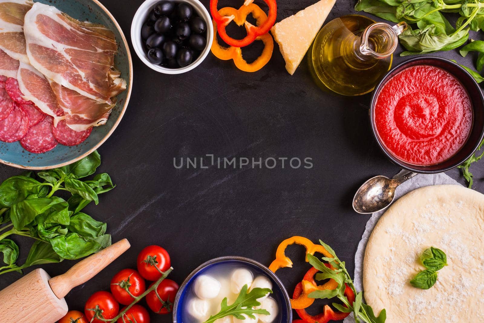 Pizza with assorted toppings and ingredients background. Space for text. Pizza, flour, cheese, tomatoes, basil, pepperoni, mushrooms and rolling pin over old wooden background. Top view. Food frame