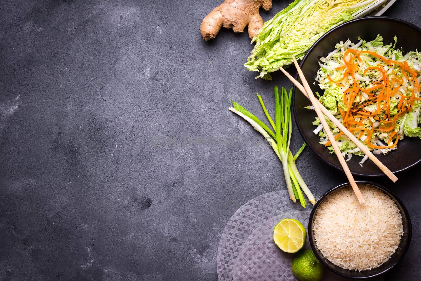 Ingredients for cooking vietnamese dinner: rice paper, rice, napa cabbage, ginger, green onion, salad. Asian cooking ingredients. Top view. Making vietnamese vegetable spring rolls. Space for text