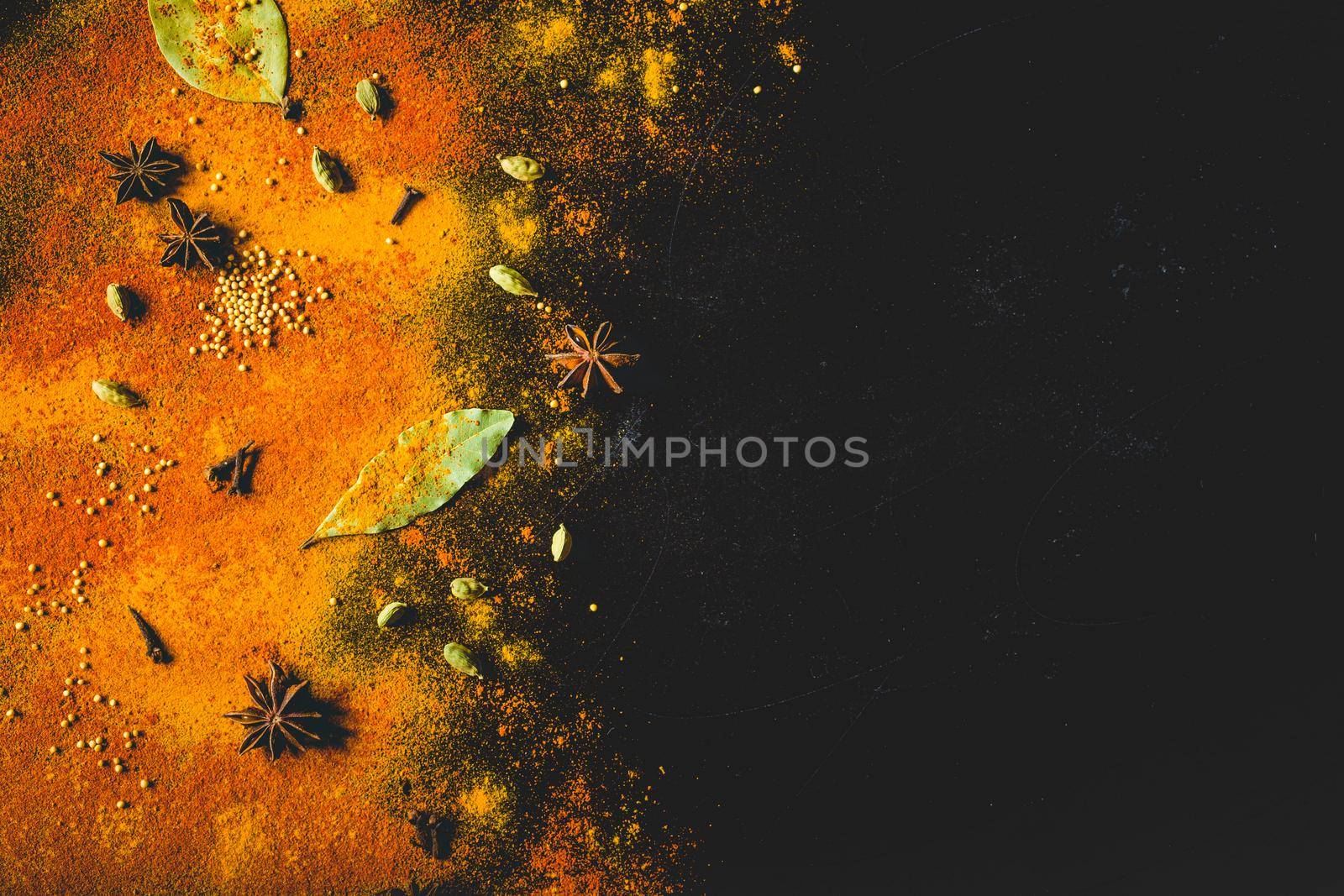 Assorted spices on dark black background. Seasonings for food. Space for text. Curry, paprika, pepper, cardamom, anise, cloves, bay leaf, turmeric. Top view. Close-up. Spices concept. Copy space