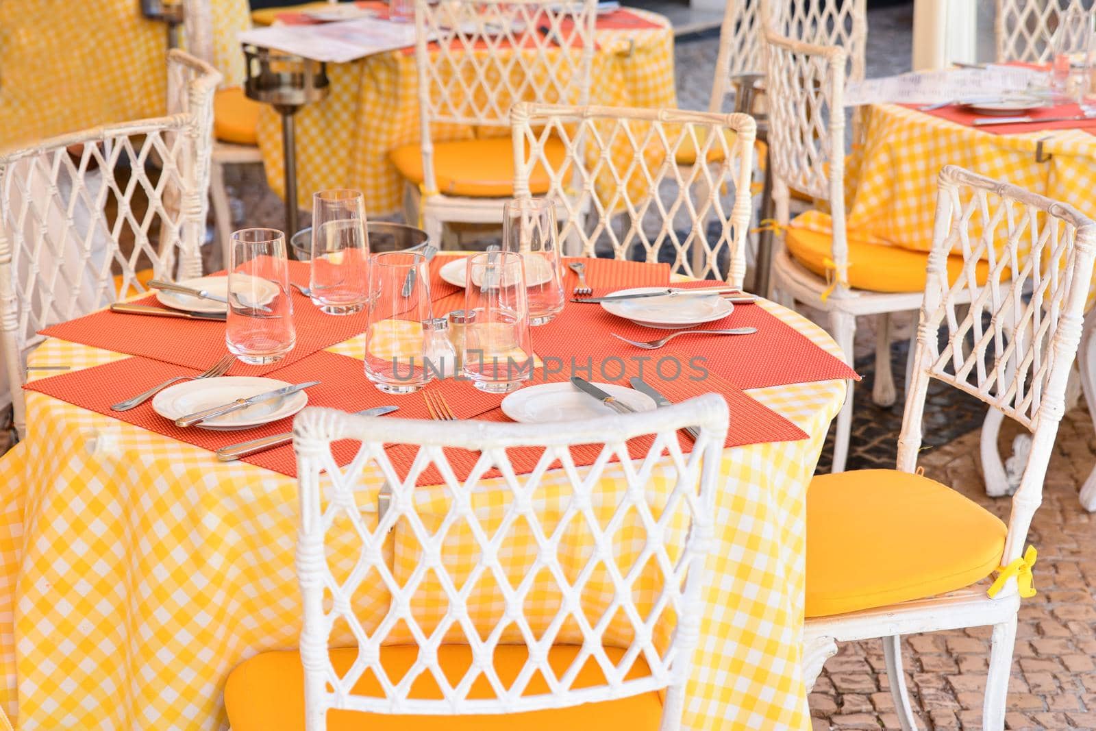 Glasses, fork, knife served for dinner in a restaurant with yellow tablecloth