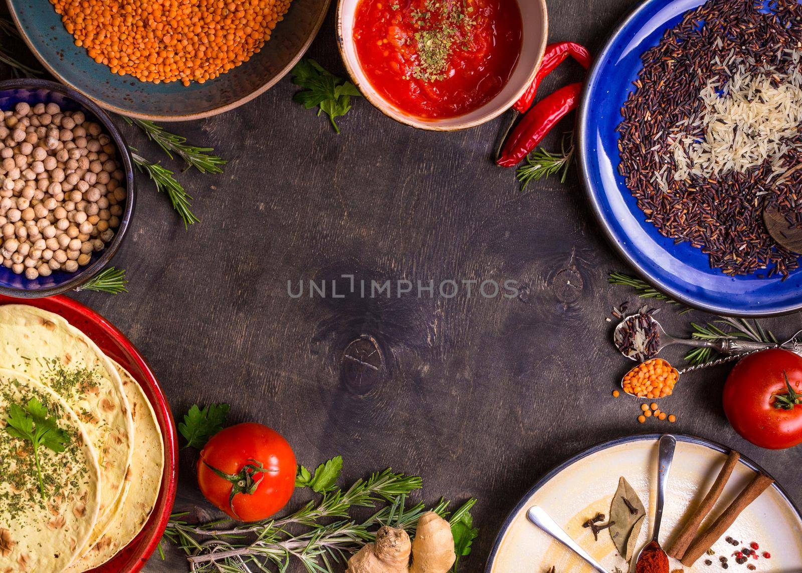 Traditional for asian or eastern cuisine cereal grains, beans, spices on colorful plates/Lentil, rice, chick-pea, tomato chutney, pita. Ingredients for indian or eastern food background/Space for text