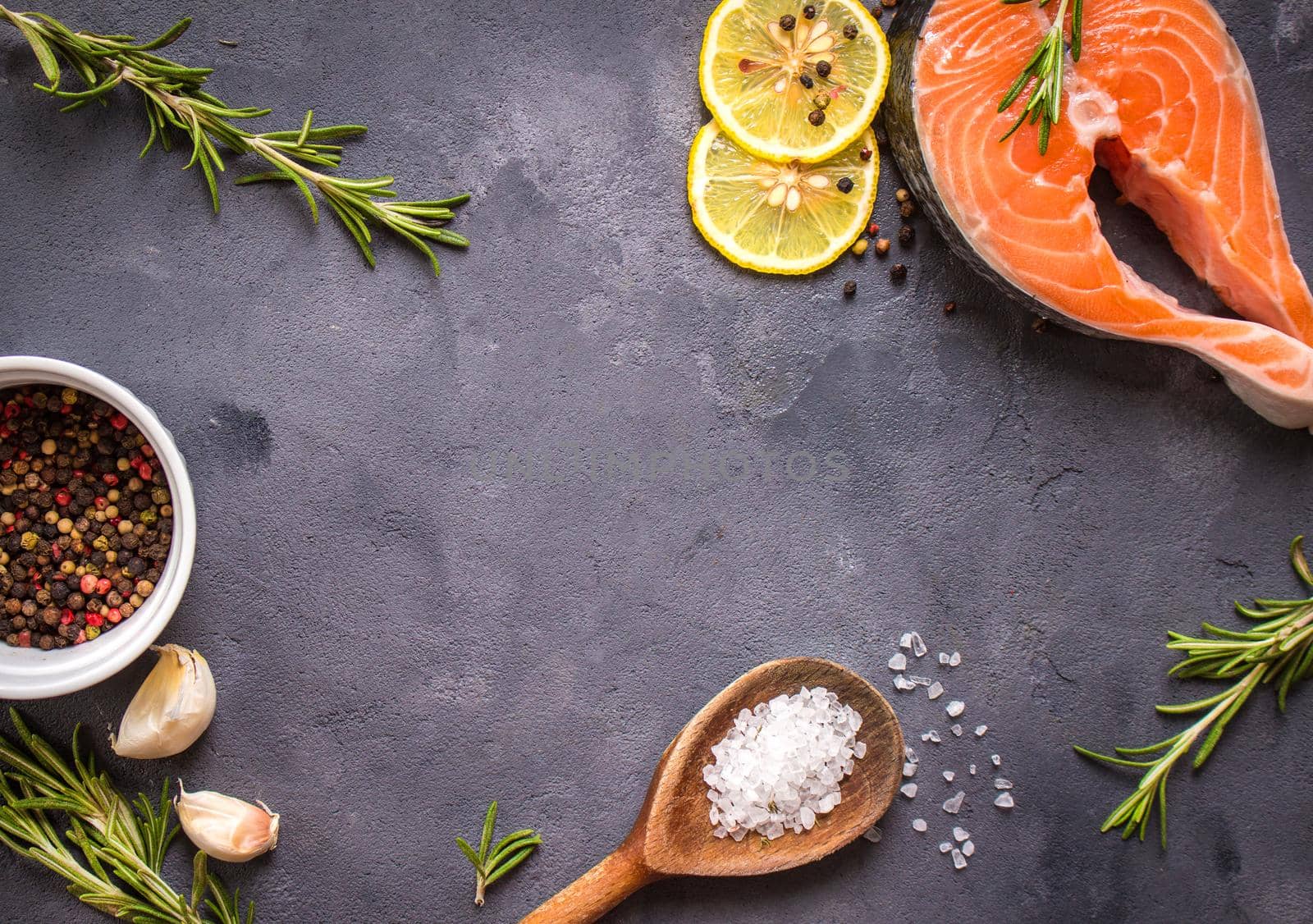 Fresh raw salmon steak, lemon, herbs, spices, wooden spoon on dark rustic concrete background. Food frame. Ingredients set for making healthy dinner. Healthy/diet concept. Space for text. Fresh fish