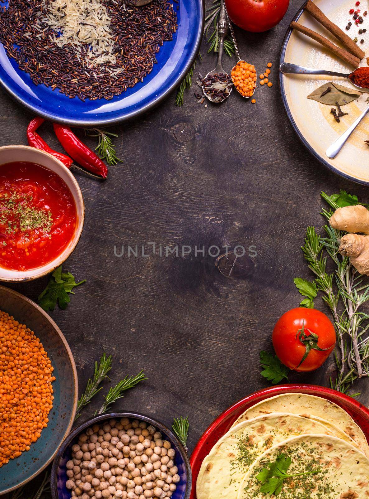 Traditional for asian or eastern cuisine cereal grains, beans, spices on colorful plates/Lentil, rice, chick-pea, tomato chutney, pita. Ingredients for indian or eastern food background/Space for text