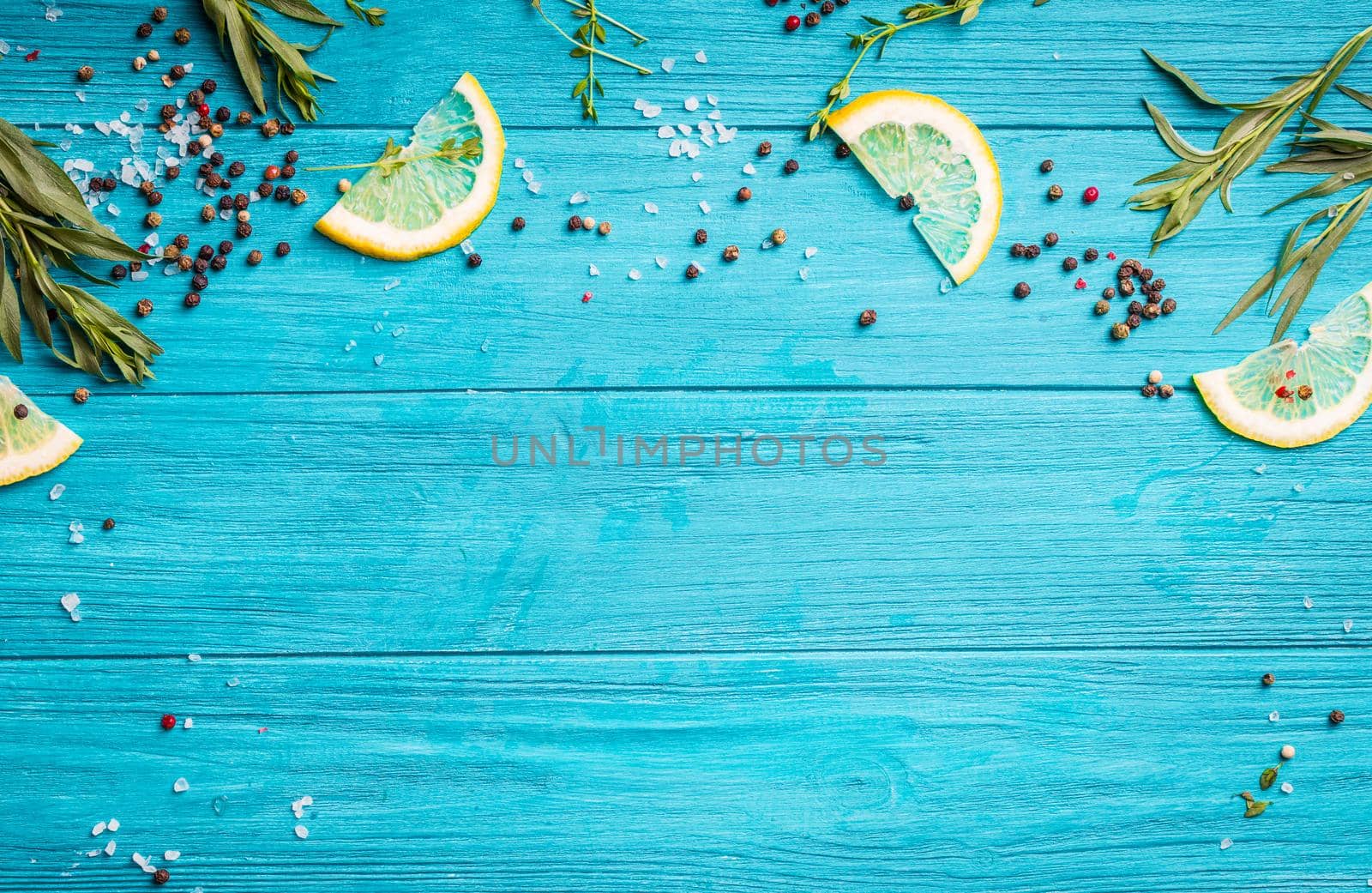 Food seasoning background. Blue coloured rustic wooden background, lemon slices, herbs, pepper, sea salt. Preparing a dinner. Space for text. Close-up. Vivid food frame. Top view. Cooking ingredients