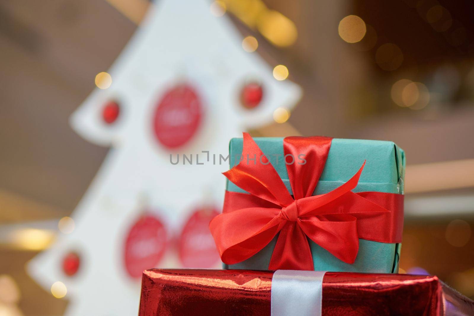 Close up wrapping gift box with ribbon. Background is christmas tree decoration