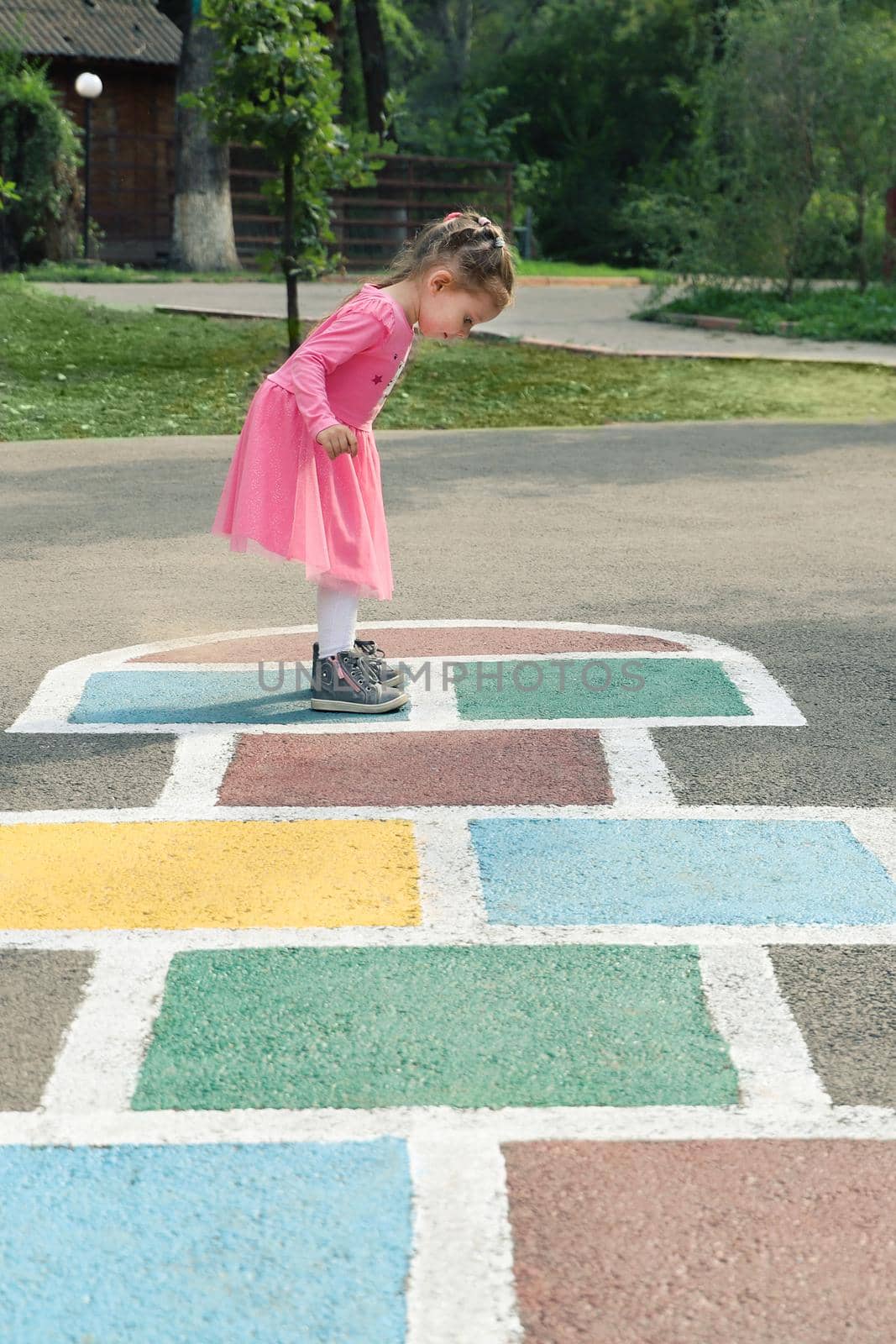 Young cute girl playing hopscotch on backyard