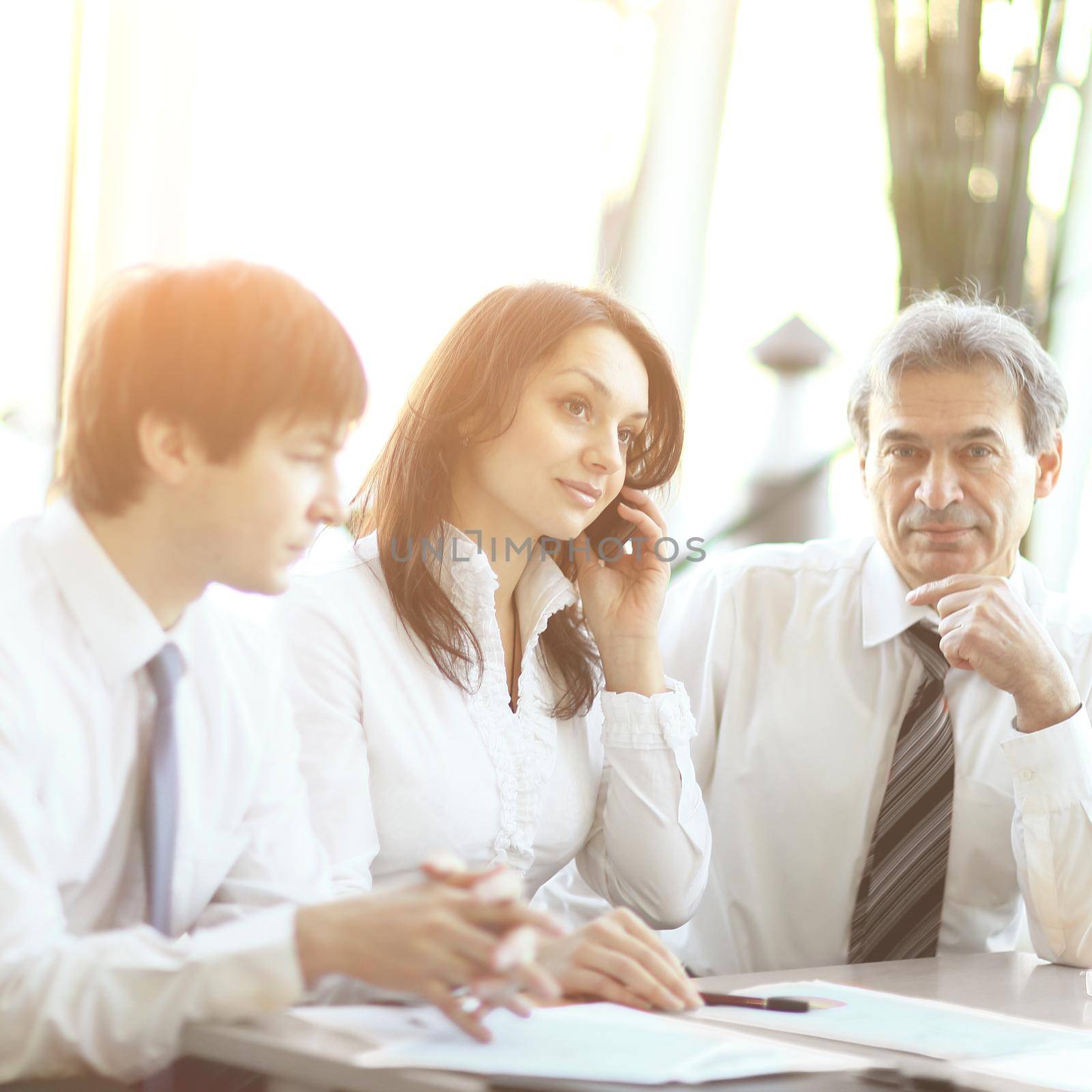 business colleagues analyzing financial statistics sitting at a Desk by SmartPhotoLab