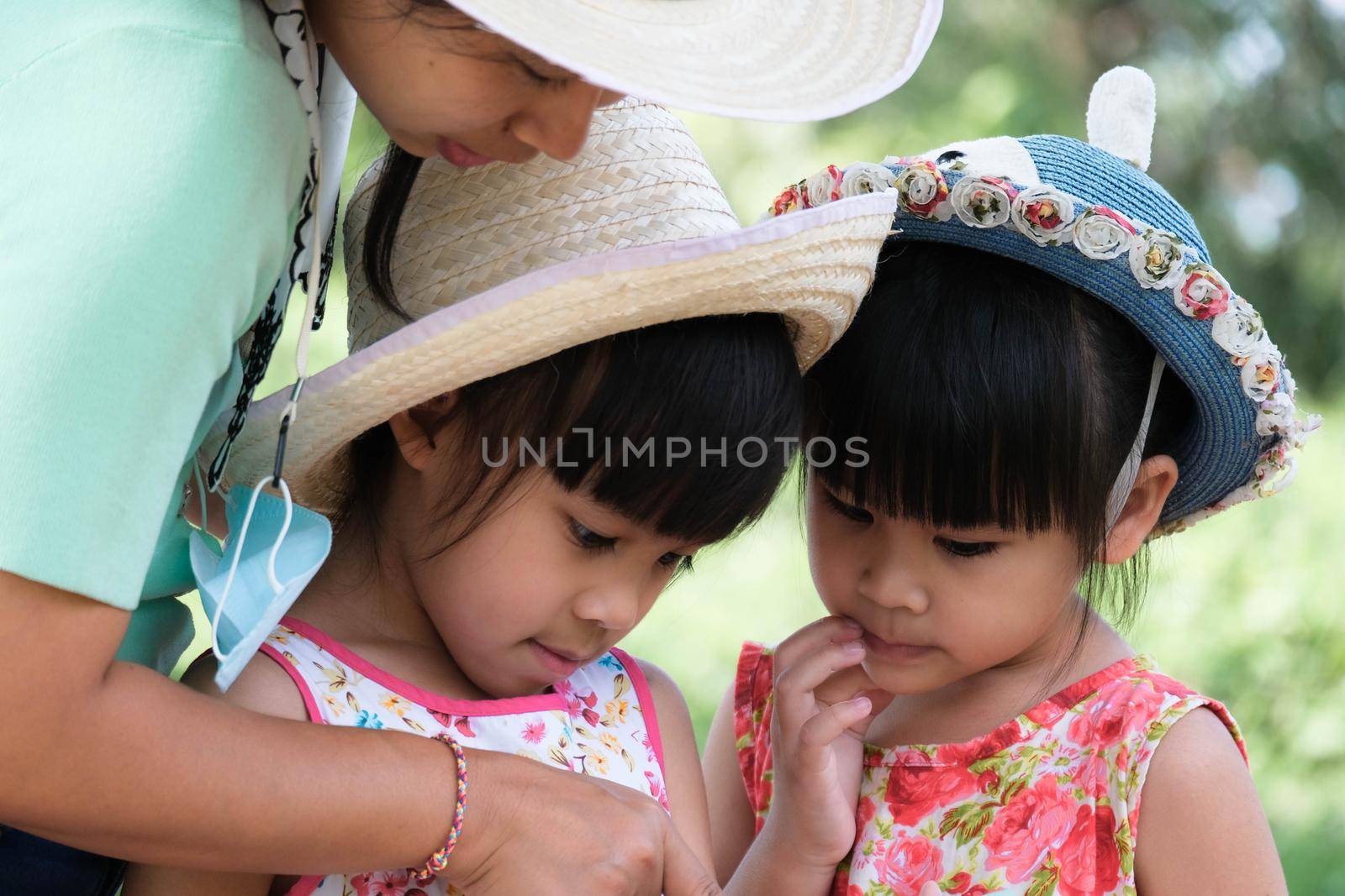 Mother and daughter use a smartphone app to find walking directions from a map in a national park. by TEERASAK