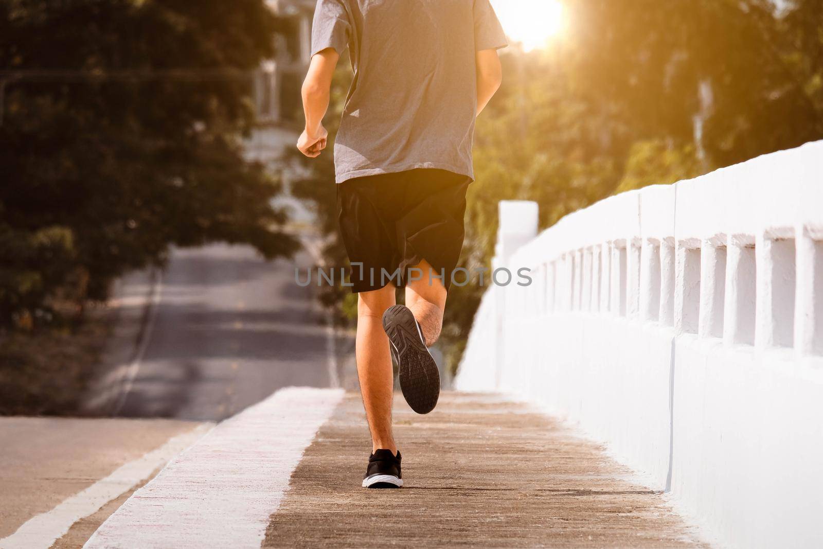 Young man runner feet running on city bridge road be running for exercise. healthy exercise concept. by TEERASAK