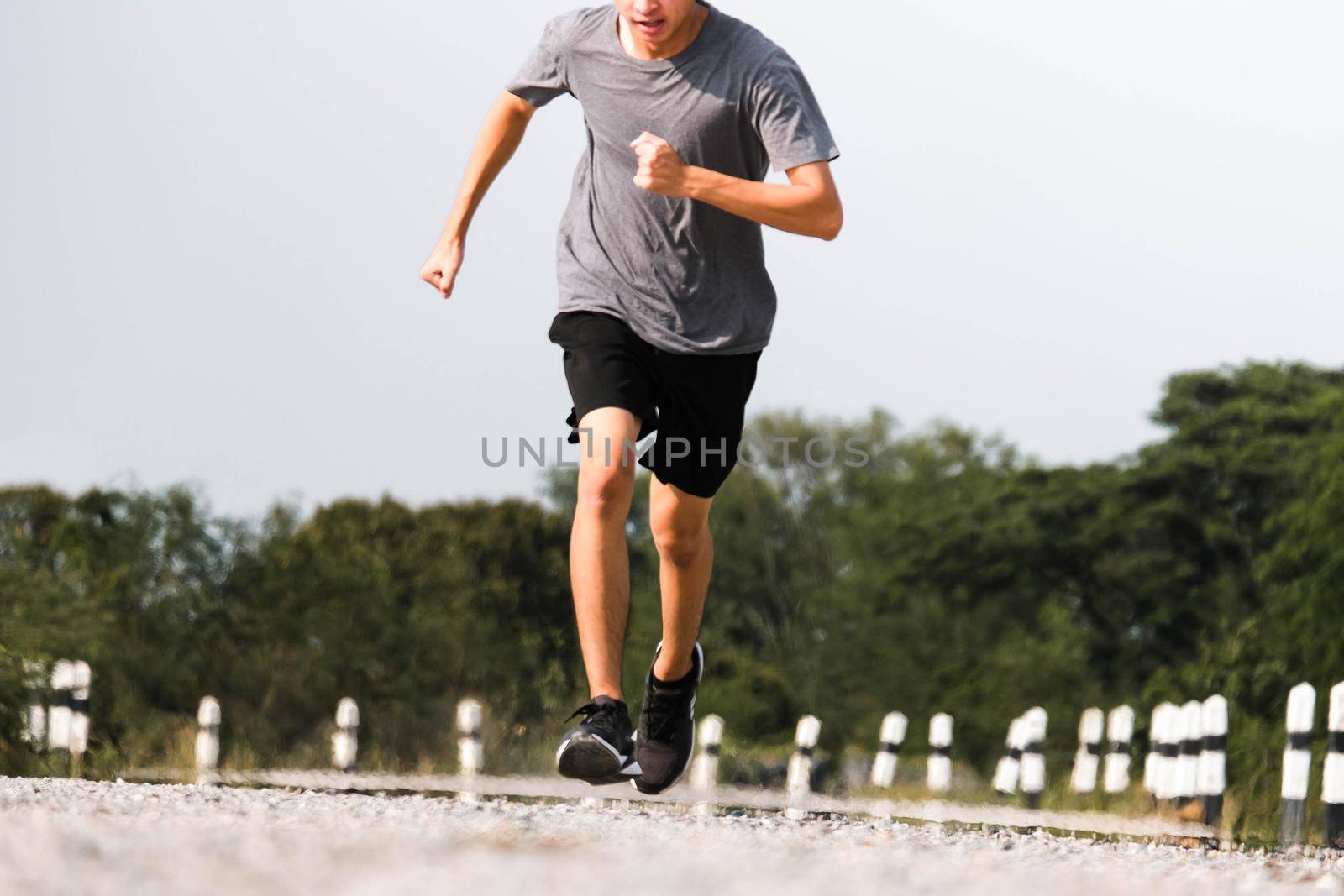 Young man runner feet running on the road be running for exercise. healthy exercise concept. by TEERASAK