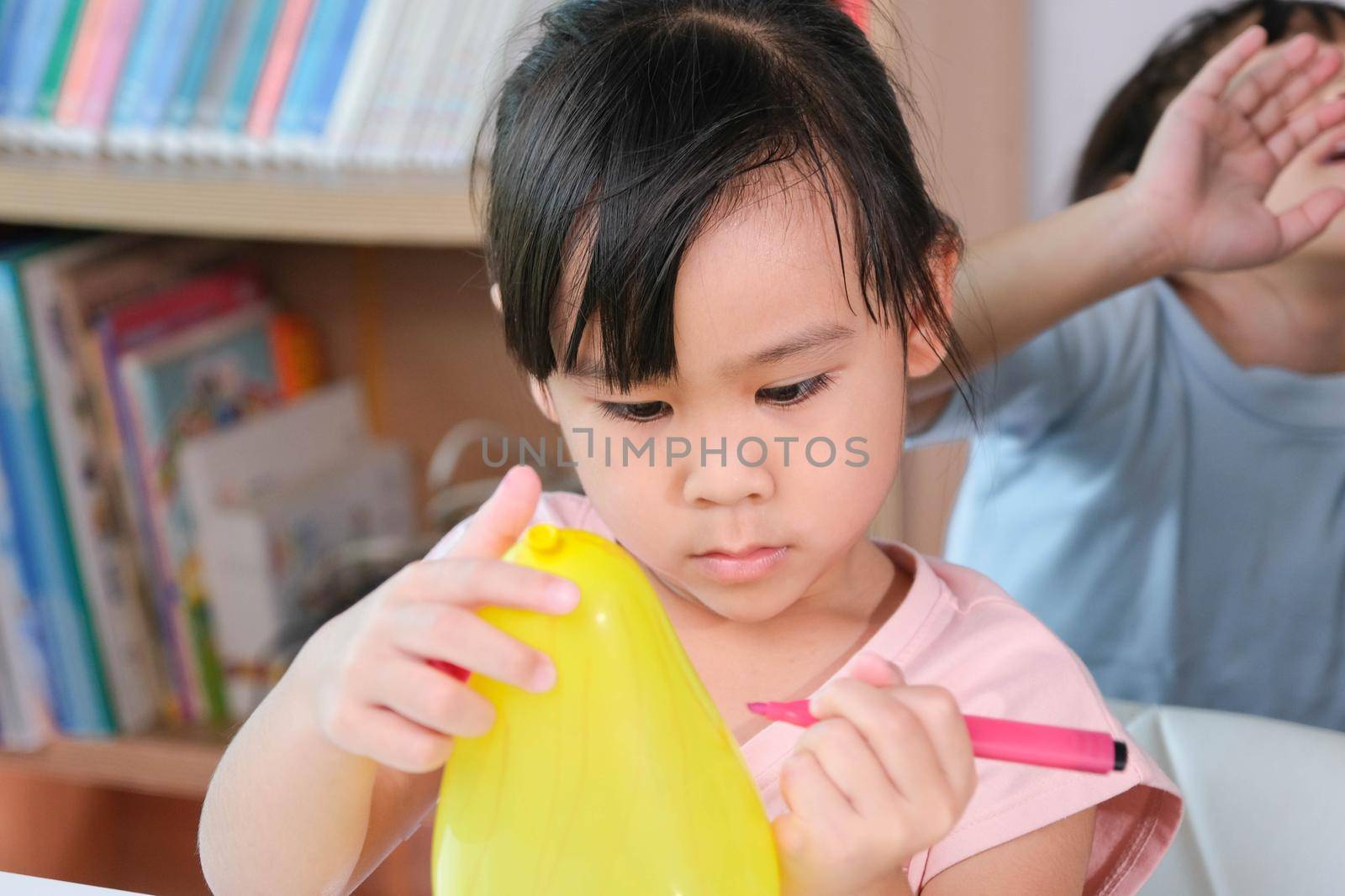 Little girl is learning and doing electrostatic science experiments with balloons in the classroom. Easy and fun science experiments for kids at home. by TEERASAK