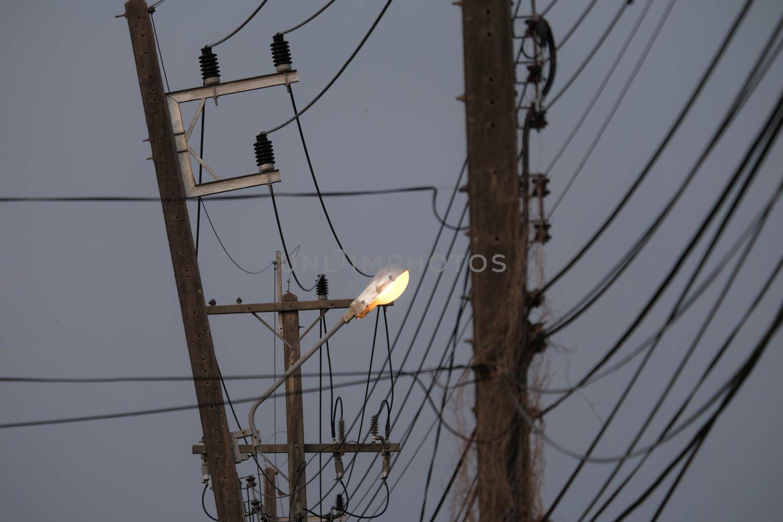 Open light bulbs on the electric pole with the wires are messed up in the evening. danger of high voltage