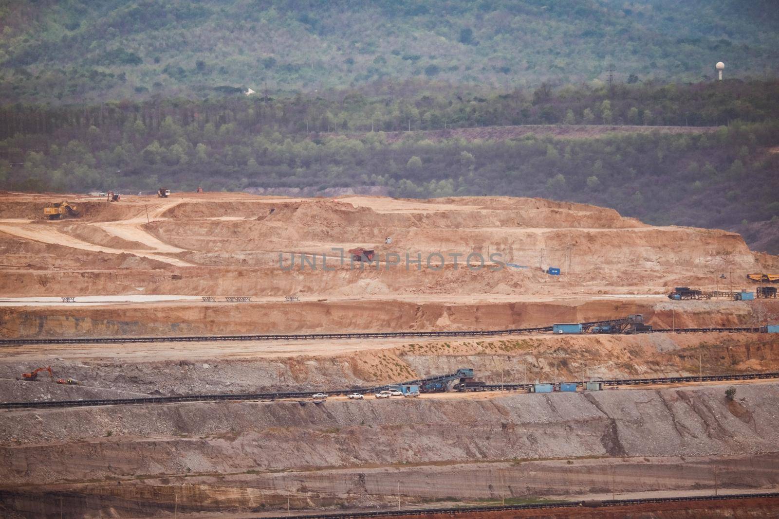 View of Trucks and excavators work in open pits in lignite coal mines. Lignite Coal Extraction Industry. The famous outdoor learning center of Mae Moh Mine Park, Lampang, Thailand.