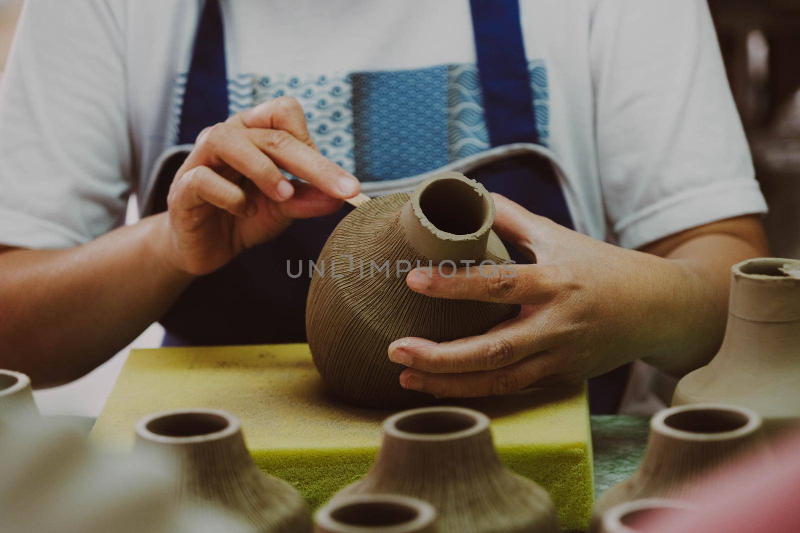 Close-up of a woman's hand making patterns on a clay vase in a pottery workshop. Process of making a ceramic vase. handicraft and small business concept.