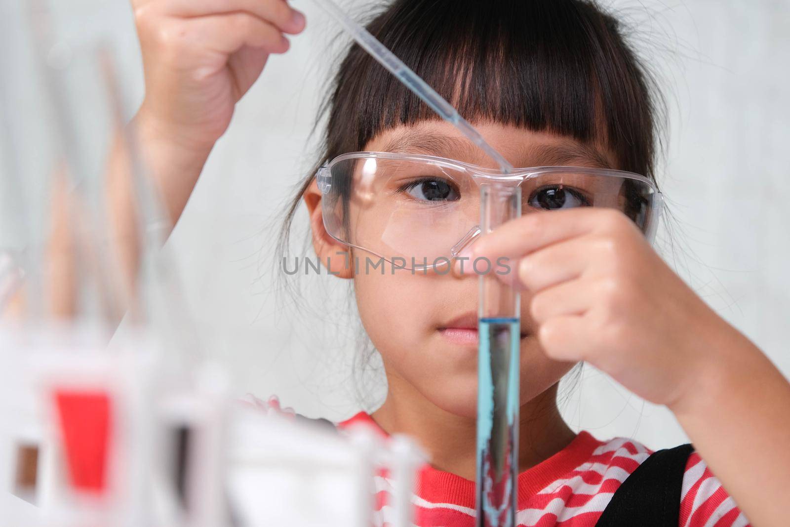 Children are learning and doing science experiments in the classroom. Little girl playing science experiment for home schooling. Easy and fun science experiments for kids at home.