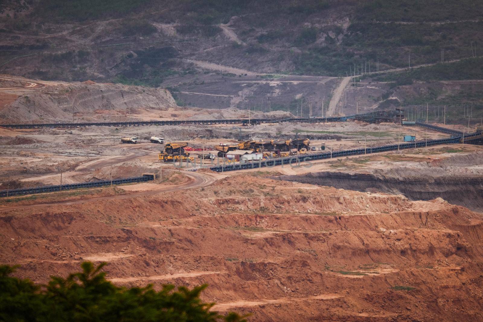 View of Trucks and excavators work in open pits in lignite coal mines. Lignite Coal Extraction Industry. The famous outdoor learning center of Mae Moh Mine Park, Lampang, Thailand.