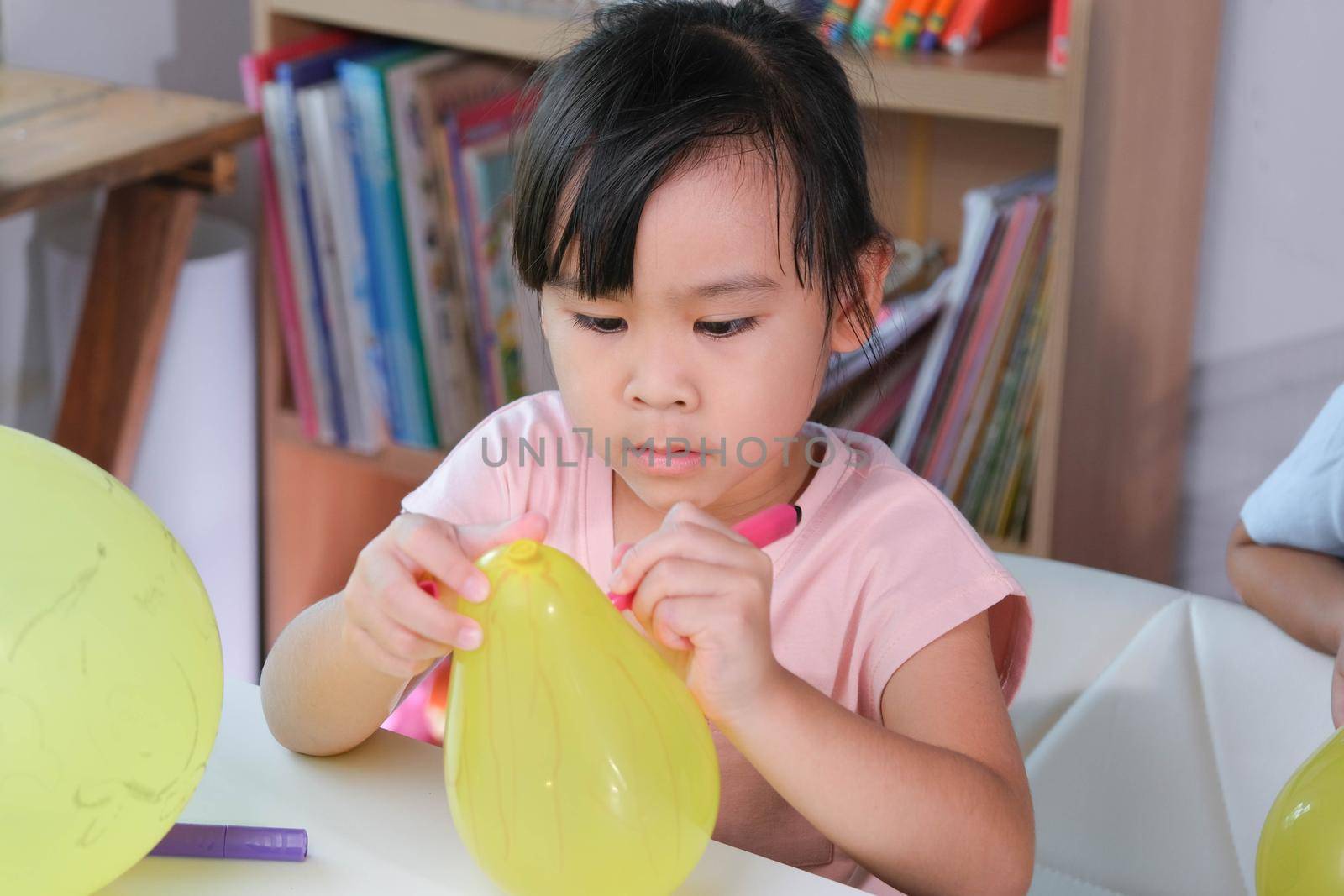 Little girl is learning and doing electrostatic science experiments with balloons in the classroom. Easy and fun science experiments for kids at home. by TEERASAK