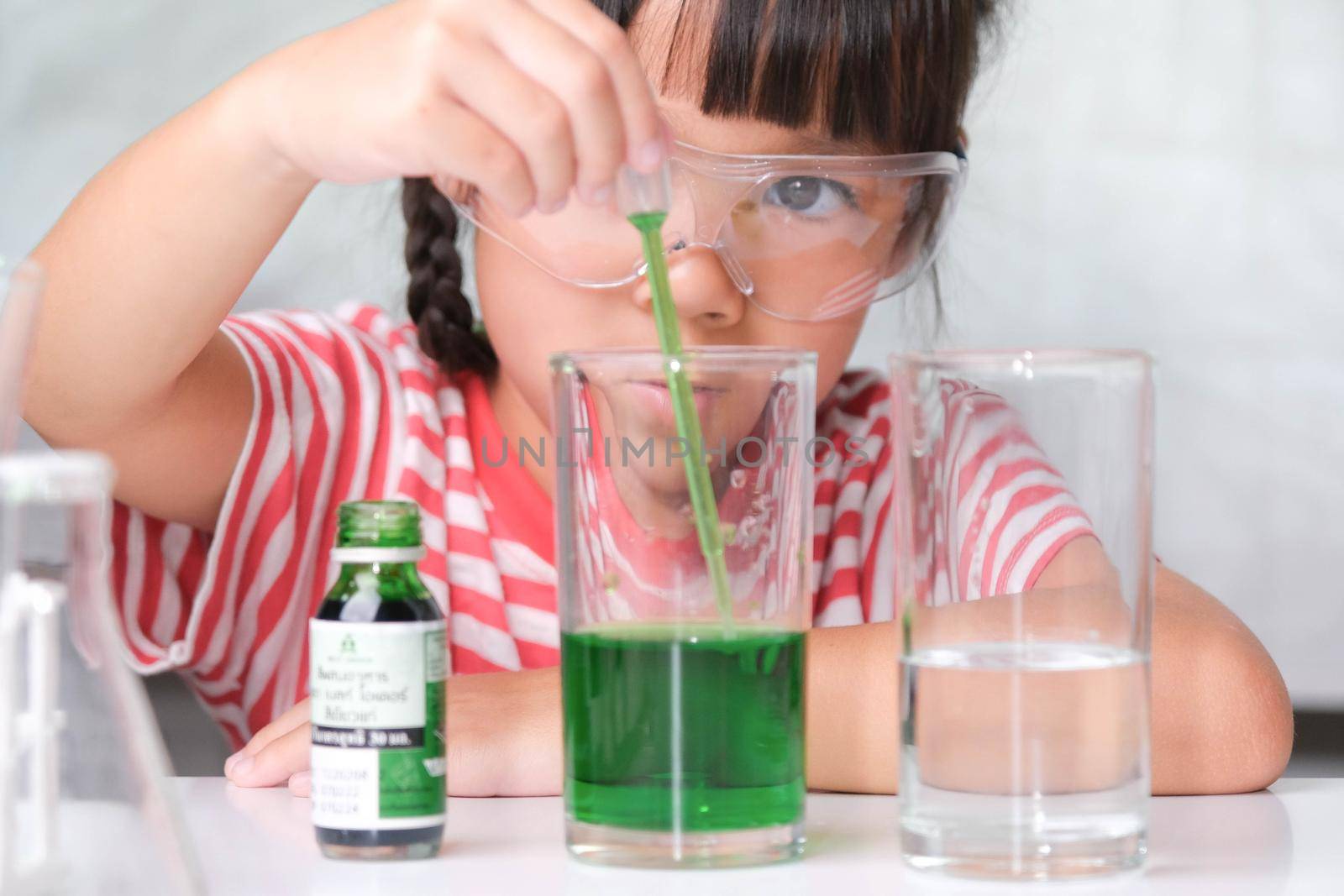 Children are learning and doing science experiments in the classroom. Little girl playing science experiment for home schooling. Easy and fun science experiments for kids at home. by TEERASAK