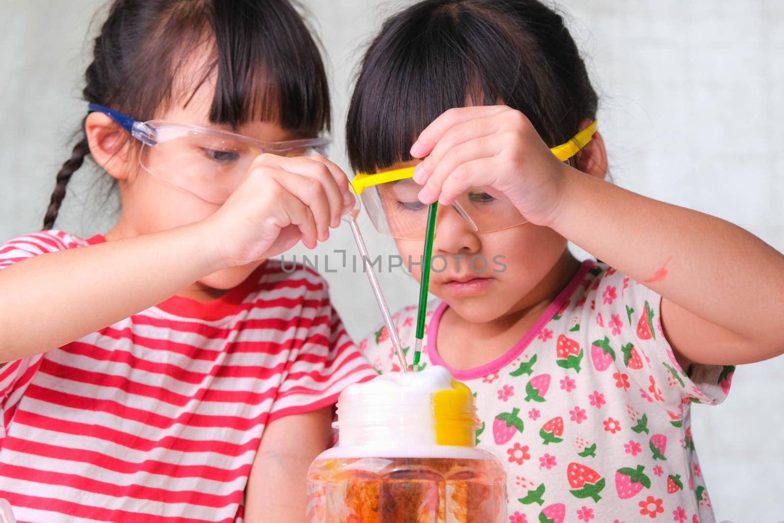 Children are learning and doing science experiments in the classroom. Two little sisters playing science experiment for home schooling. Easy and fun science experiments for kids at home. by TEERASAK