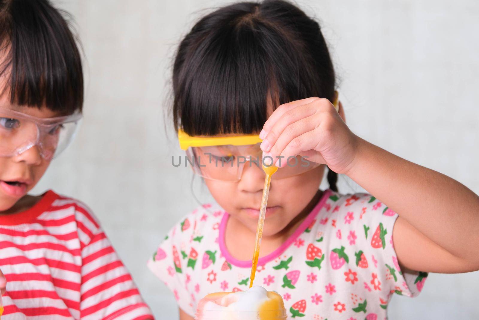 Children are learning and doing science experiments in the classroom. Two little sisters playing science experiment for home schooling. Easy and fun science experiments for kids at home.