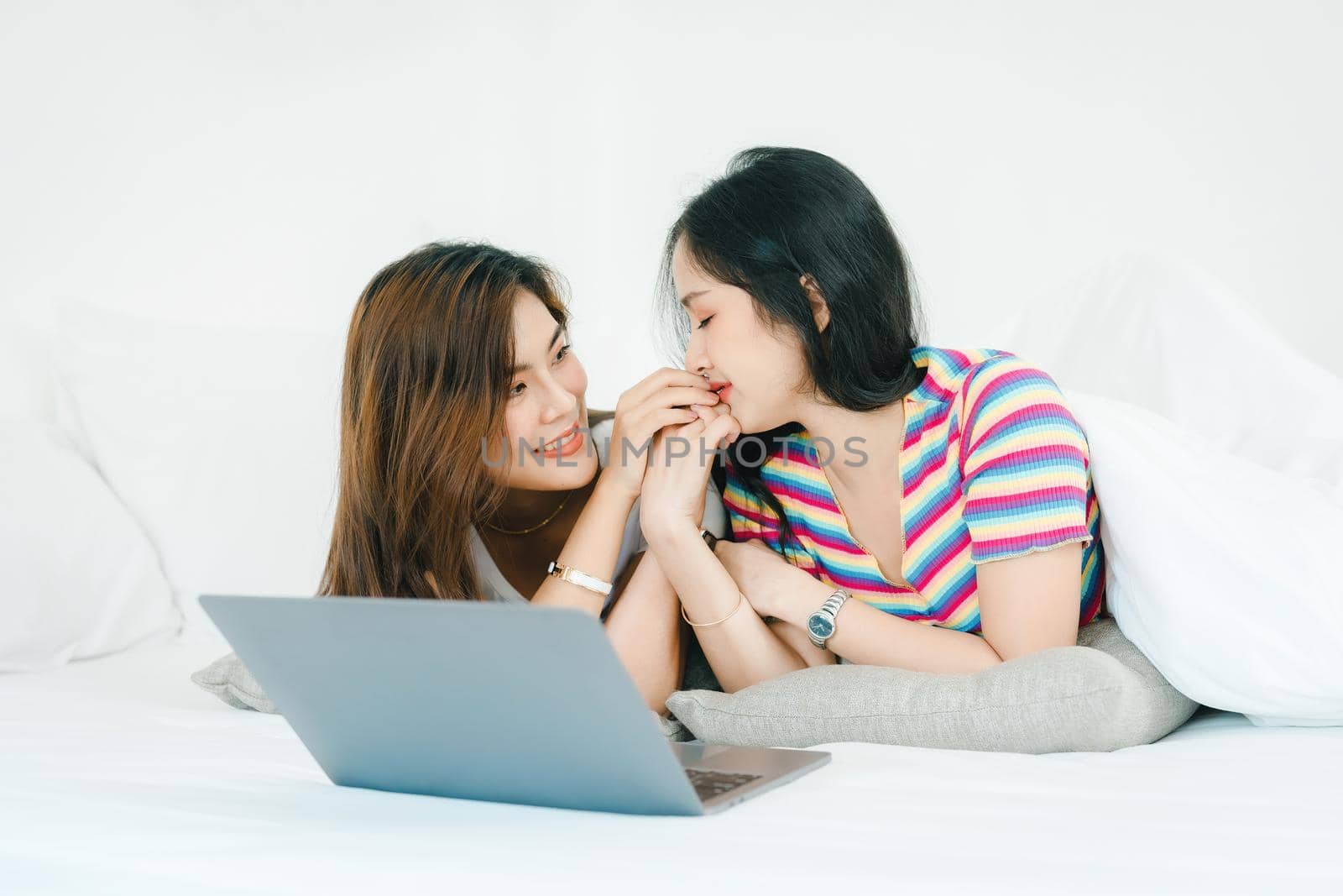 lgbtq, lgbt concept, homosexuality, portrait of two asian women posing happy together and loving each other while playing computer laptop on bed by Manastrong