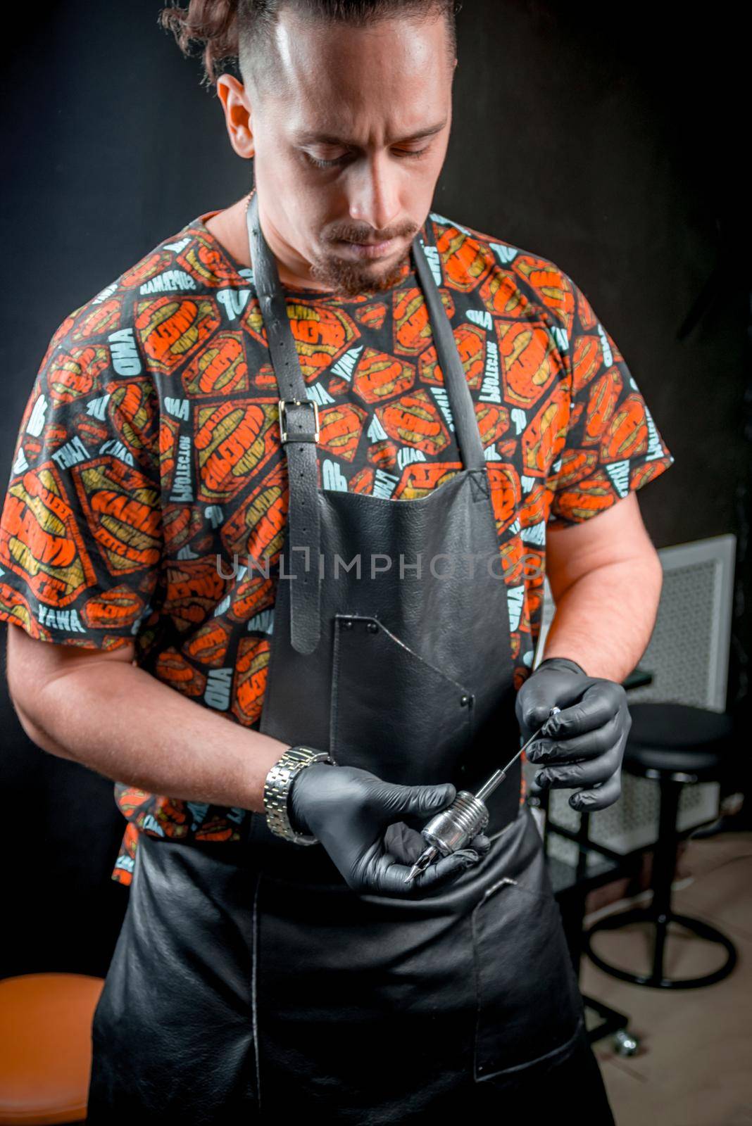 Tattoo specialist with a tattoo gun in a tattoo studio by Proff