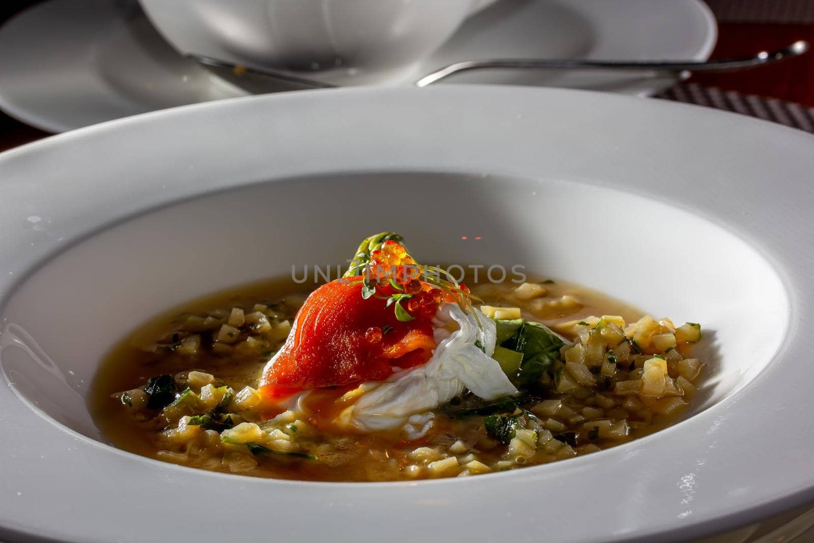 Traditional russian soup - okroshka with fresh vegetables, meat and kvass. Cold summer soup on white table. Aesthetic composition with traditional russian food and spices, textile, spoon