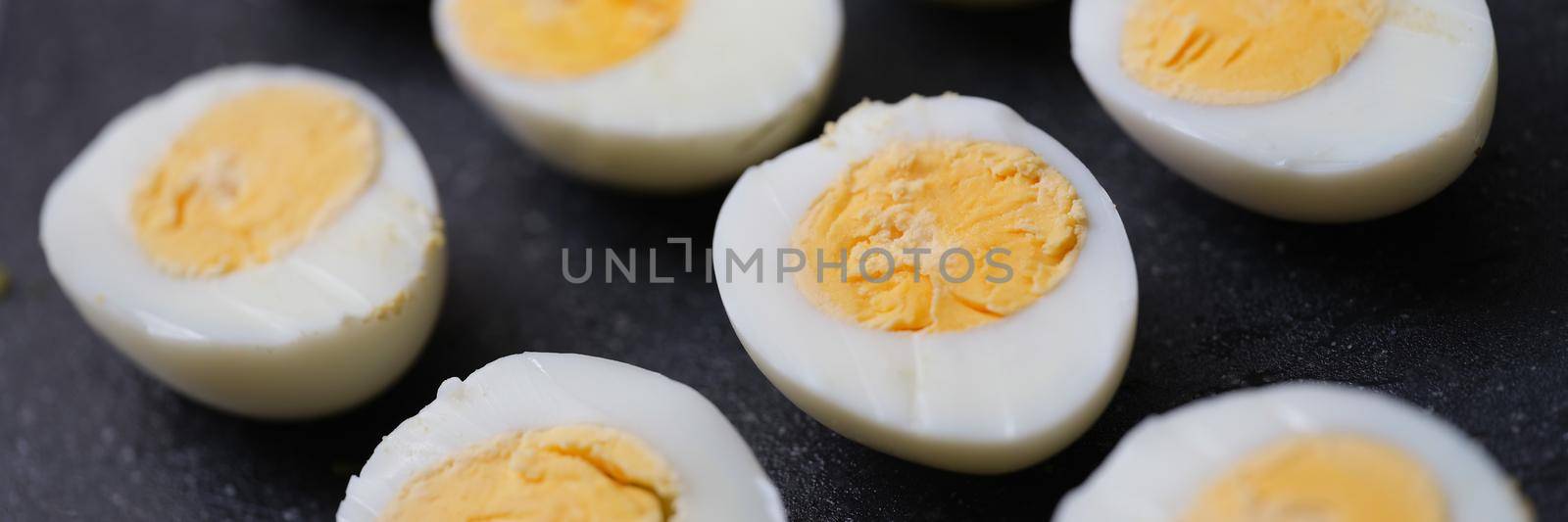 Chicken halves boiled eggs set on a black background, close-up. Harmless food, organic production. Calorie content of food