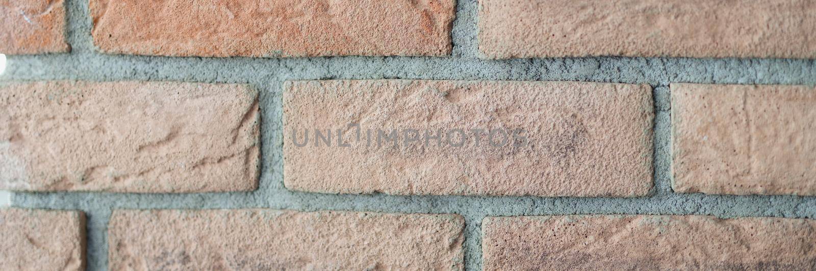 Red brick wall in the interior, rough texture, close-up. Design element, old brickwork with cement. Orange exterior facade