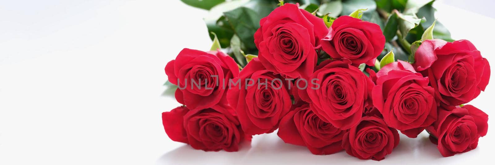 A large beautiful bouquet of red roses lies on the table, close-up. Seasonal bouquet of flowers, home delivery of gifts