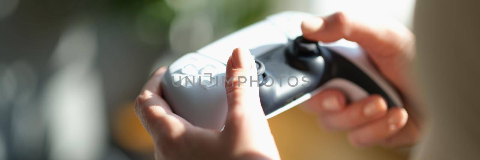 Beautiful female hands hold a joystick for the game, close-up. Video game addiction, gaming accessories, device
