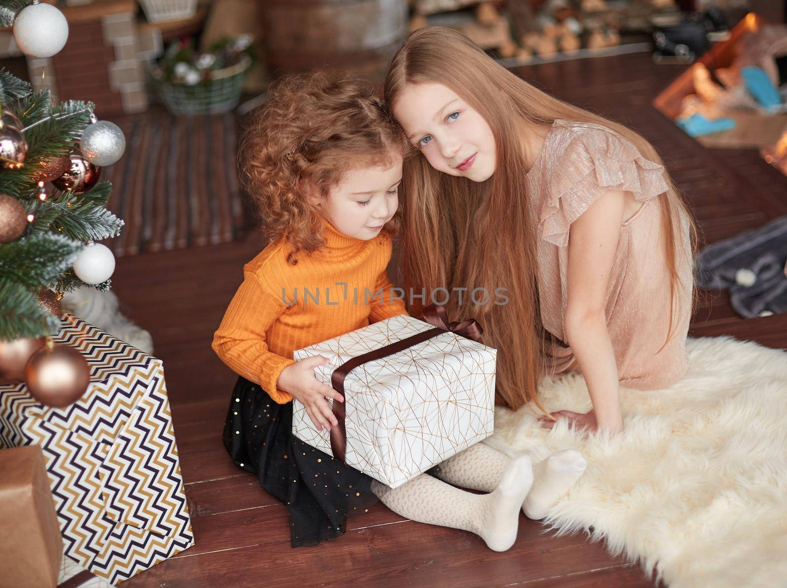 two pretty sisters sitting on the floor on Christmas eve. holiday concept