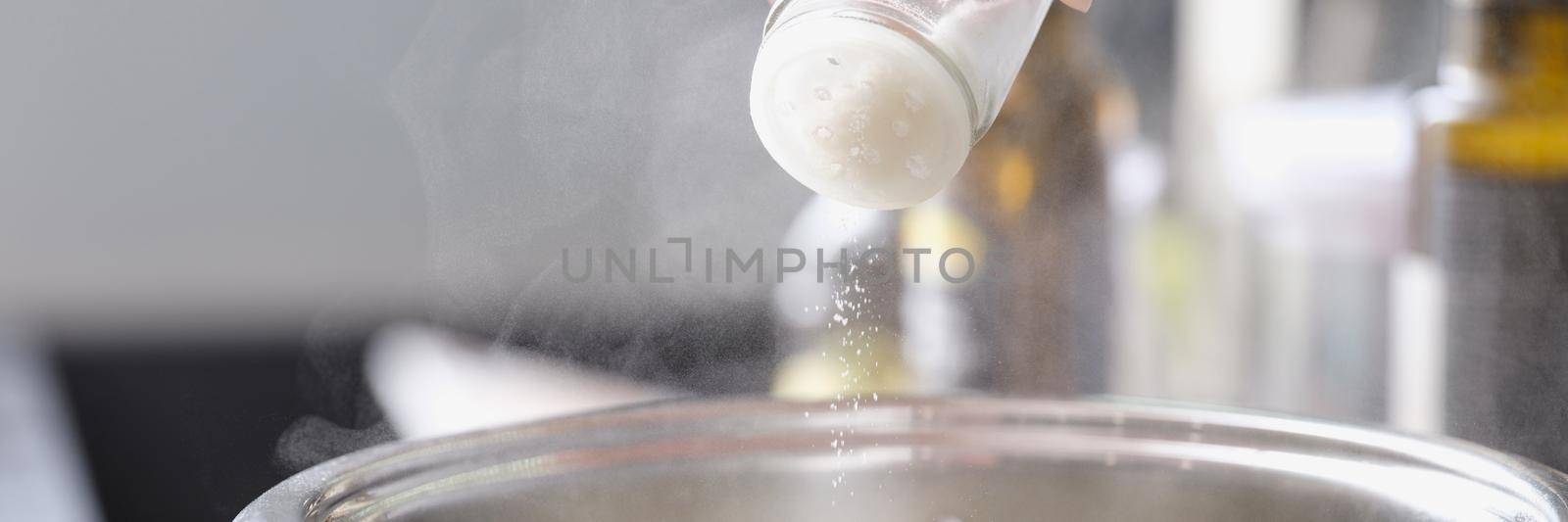 Woman prepares food in a saucepan and salt by kuprevich