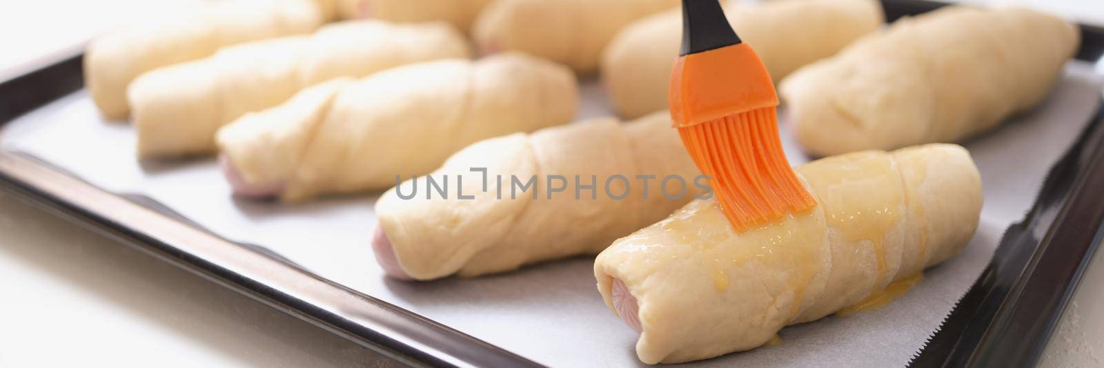 A woman before baking with a brush lubricates dough products, close-up. Delicious homemade cakes, family meal preparation
