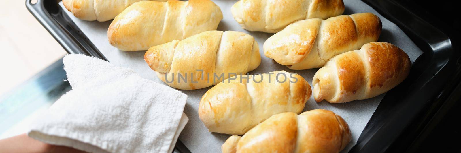 A woman takes buns out of the oven on a baking sheet, close-up. Homemade bread, baking at home, organic food